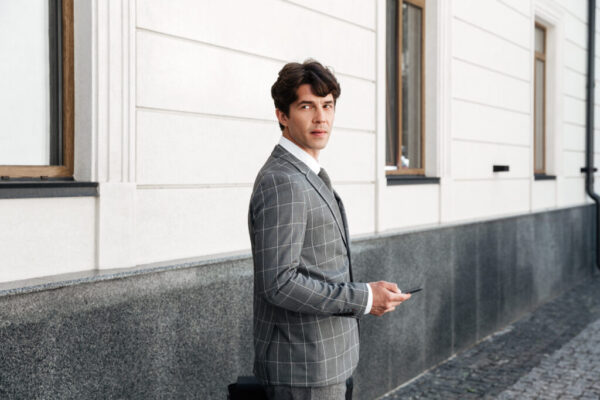 Confident businessman in suit holding car keys while standing outdoors at the office building