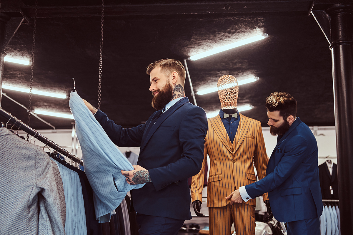 Two stylish shop assistants elegantly dressed working in menswear store.